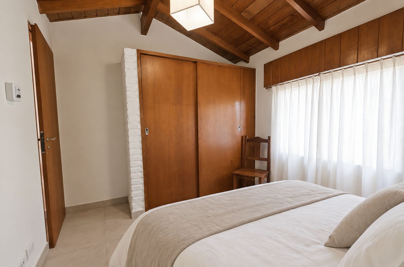 Dormitorio principal con cama matrimonial, techo de vigas de madera y placard